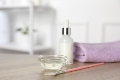 Photo of Peeling procedure. Bottle of chemical peel, bowl with liquid, towel and brush on wooden table indoors. Space for text