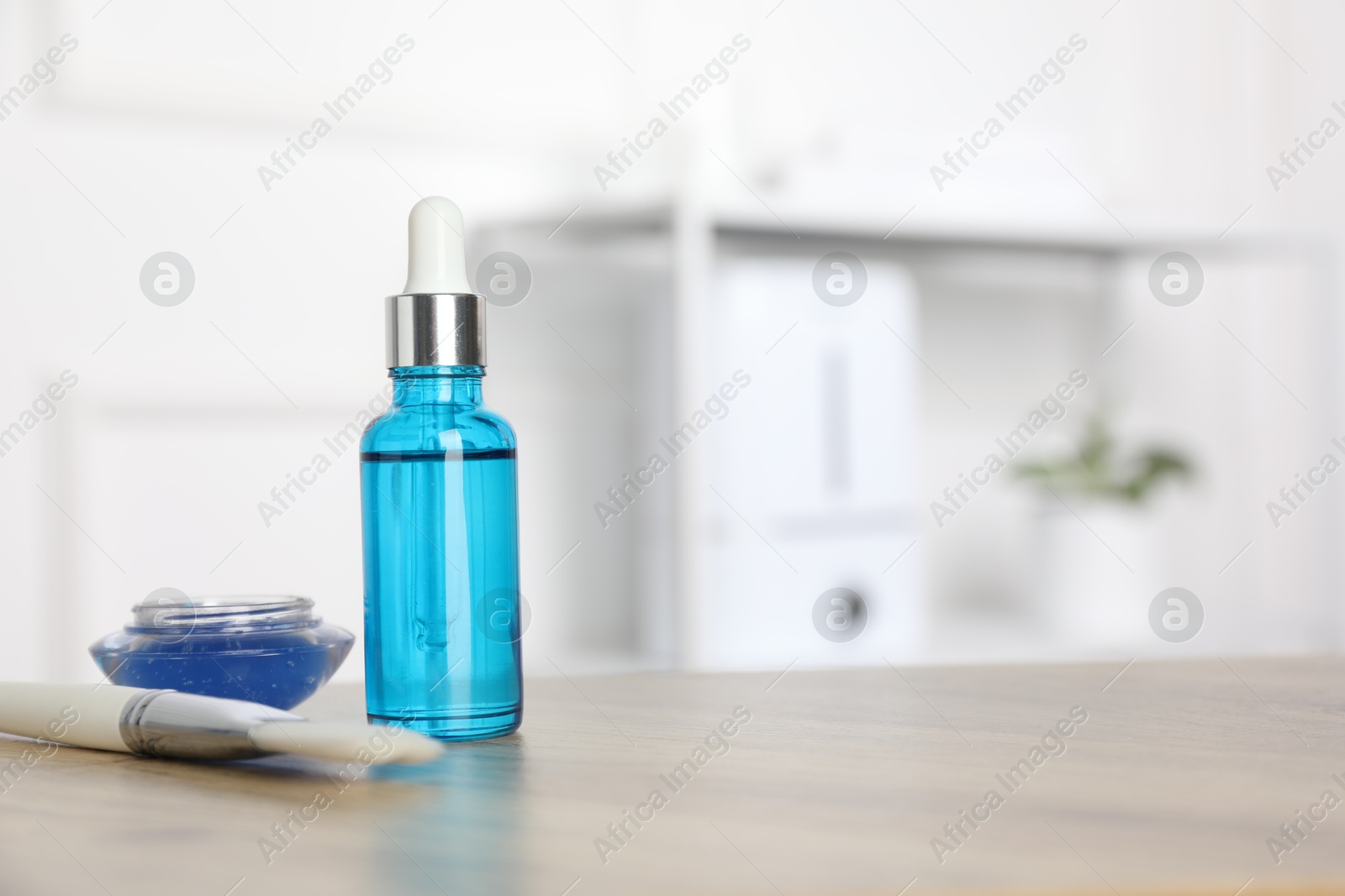 Photo of Peeling procedure. Bottle of chemical peel, bowl with liquid and brush on wooden table indoors. Space for text