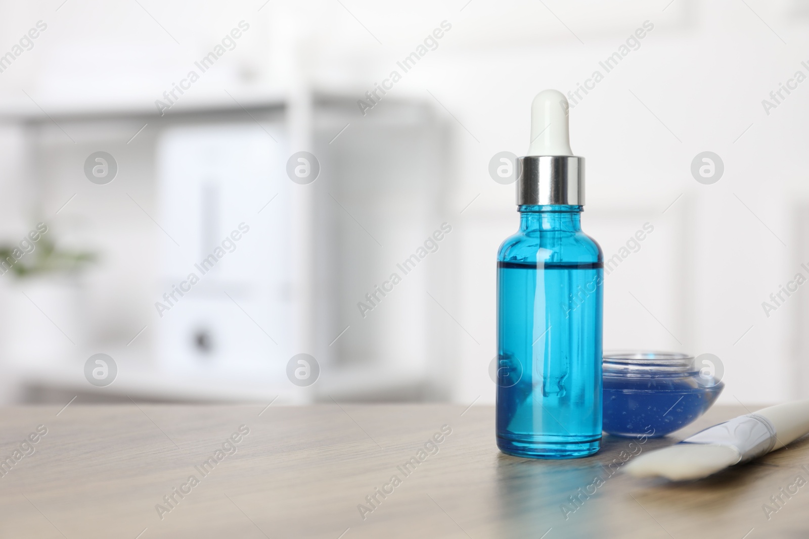 Photo of Peeling procedure. Bottle of chemical peel, bowl with liquid and brush on wooden table indoors. Space for text