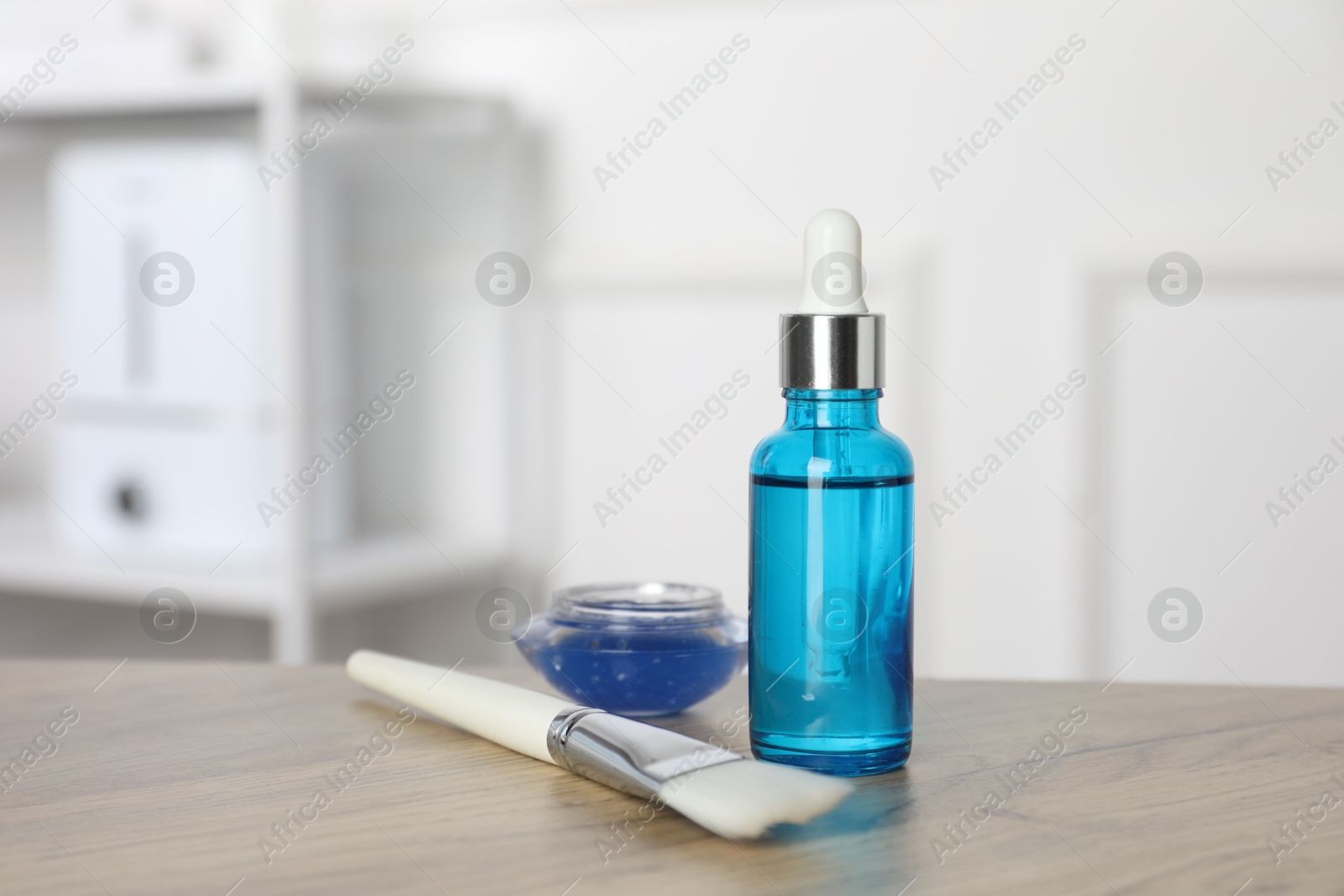 Photo of Peeling procedure. Bottle of chemical peel, bowl with liquid and brush on wooden table indoors