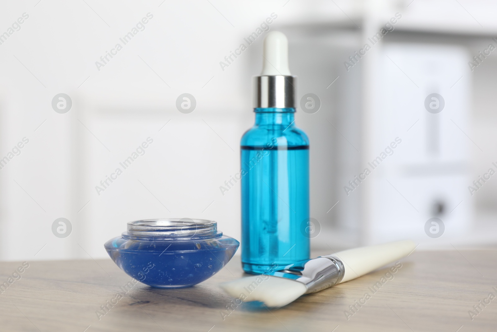 Photo of Peeling procedure. Bottle of chemical peel, bowl with liquid and brush on wooden table indoors