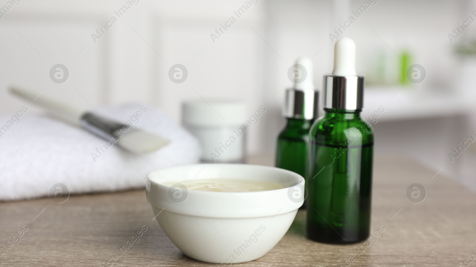 Photo of Peeling procedure. Bottles of chemical peel, bowl with liquid and brush on wooden table indoors. Space for text