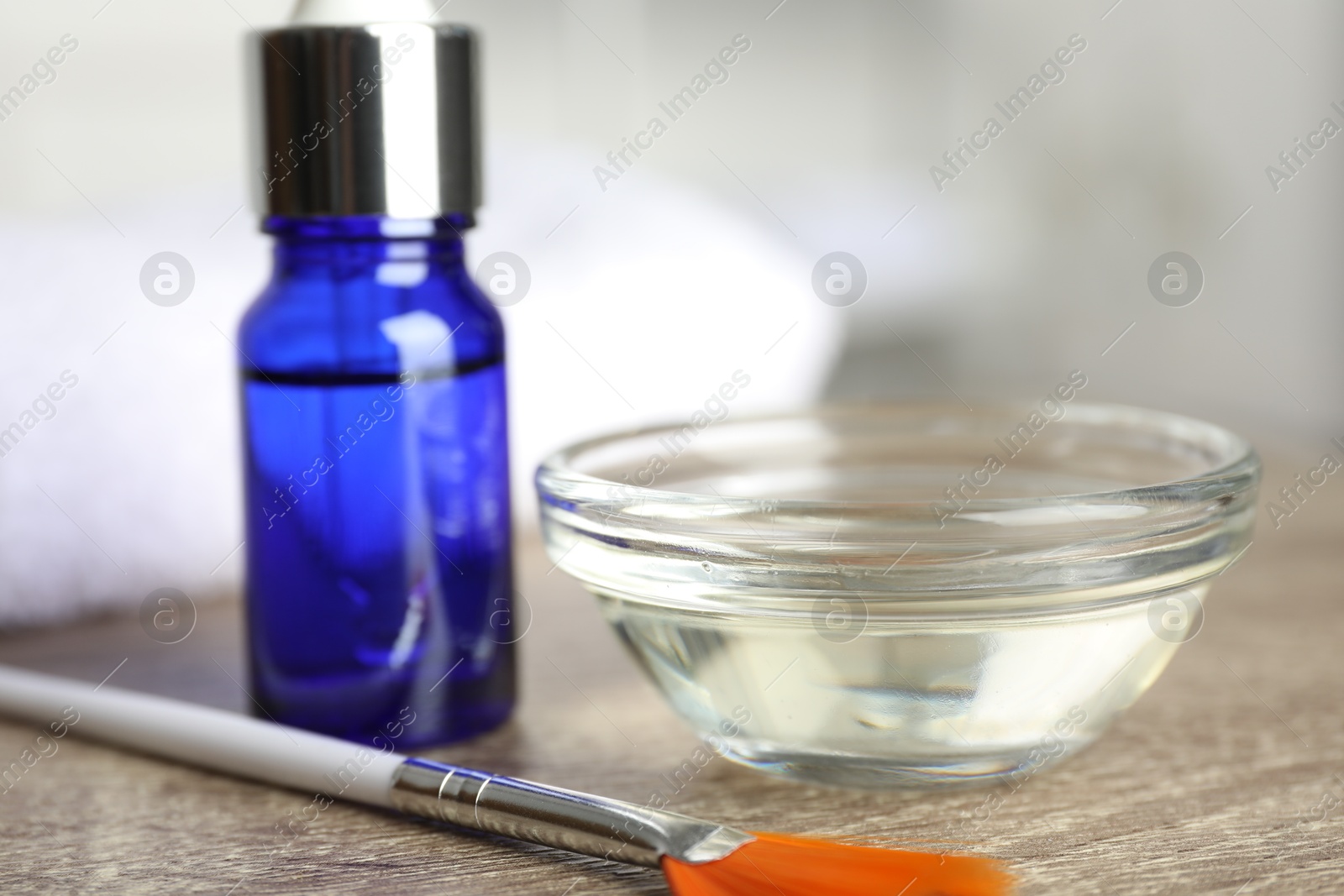 Photo of Peeling procedure. Bottle of chemical peel, bowl with liquid and brush on wooden table, closeup