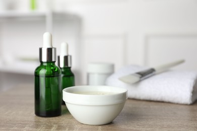 Photo of Peeling procedure. Bottles of chemical peel, bowl with liquid and brush on wooden table indoors. Space for text