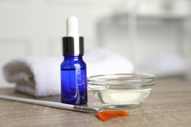 Photo of Peeling procedure. Bottle of chemical peel, bowl with liquid and brush on wooden table indoors