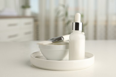 Photo of Peeling procedure. Bottle of chemical peel, bowl with liquid and brush on white table indoors