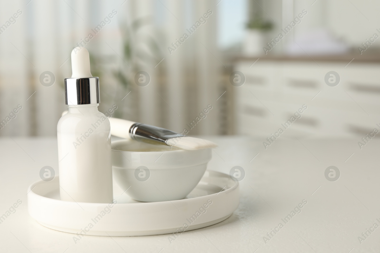 Photo of Peeling procedure. Bottle of chemical peel, bowl with liquid and brush on white table indoors. Space for text