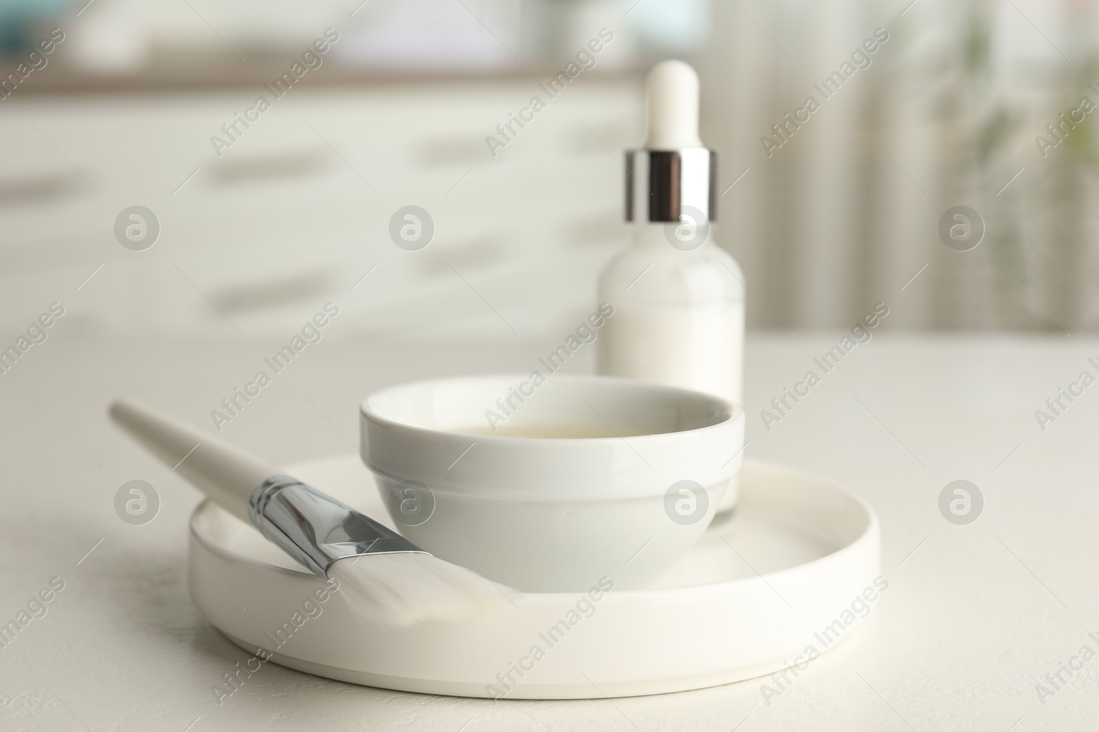 Photo of Peeling procedure. Bottle of chemical peel, bowl with liquid and brush on white table indoors