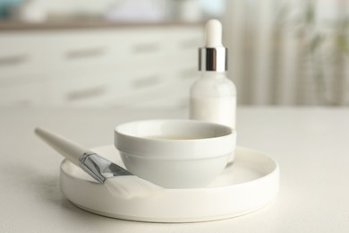 Photo of Peeling procedure. Bottle of chemical peel, bowl with liquid and brush on white table indoors