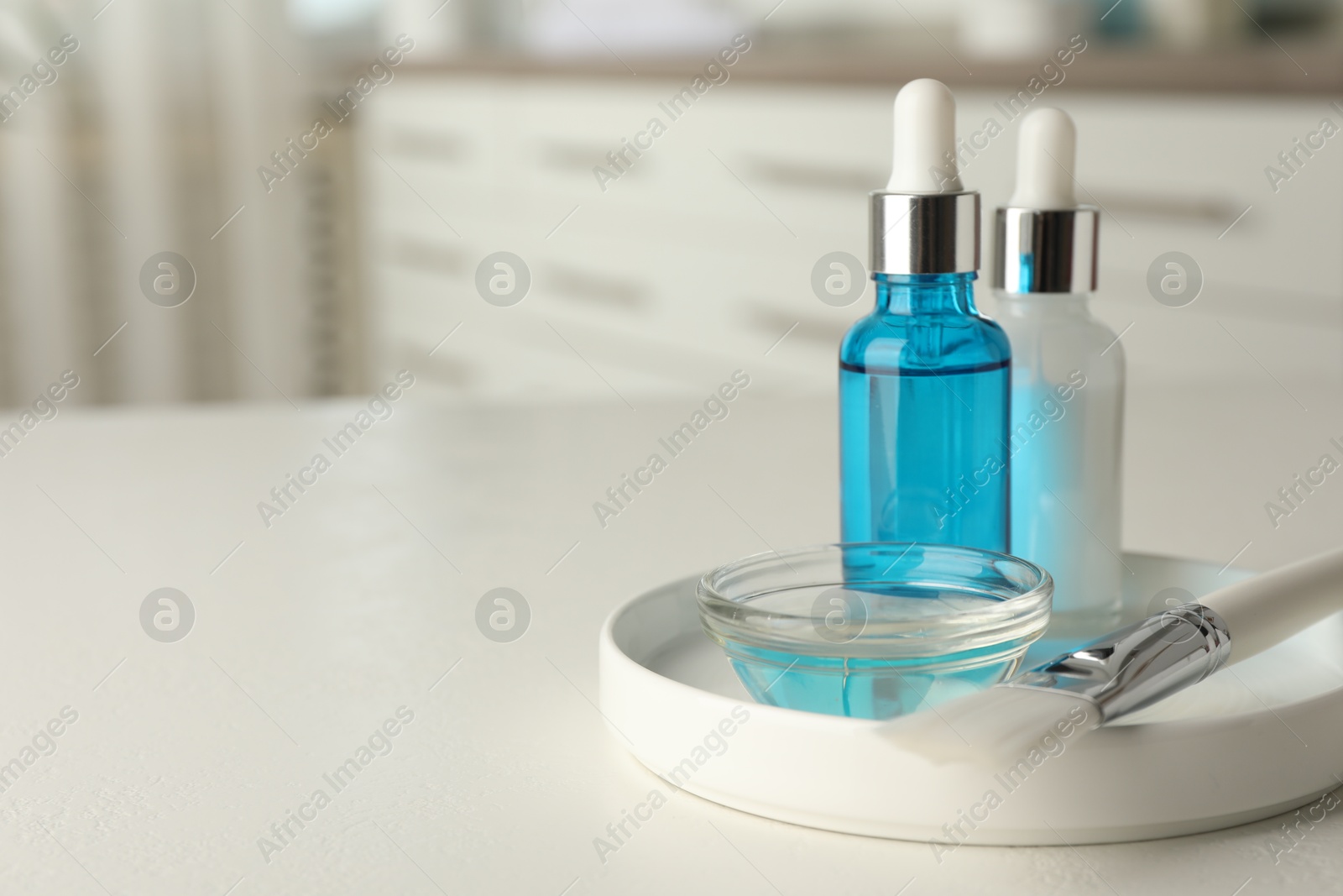 Photo of Peeling procedure. Bottles of chemical peel, bowl with liquid and brush on white table indoors. Space for text