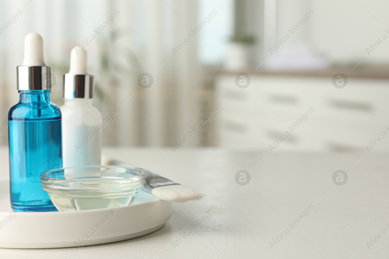 Photo of Peeling procedure. Bottles of chemical peel, bowl with liquid and brush on white table indoors. Space for text