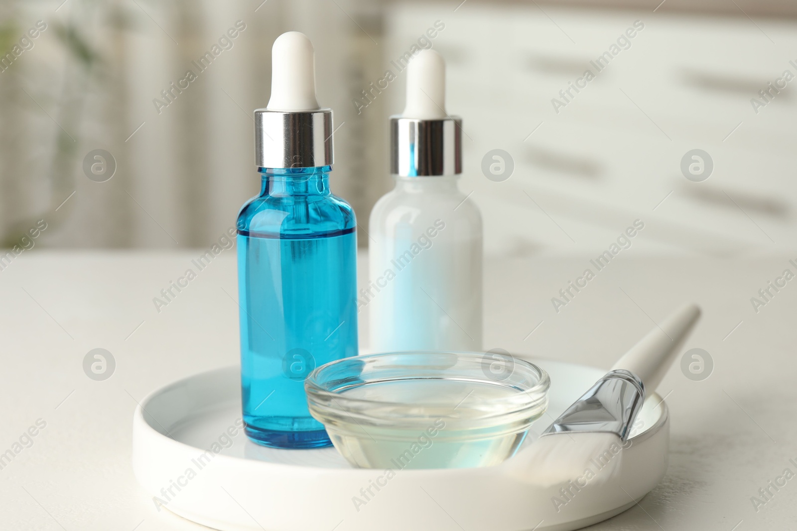 Photo of Peeling procedure. Bottles of chemical peel, bowl with liquid and brush on white table indoors