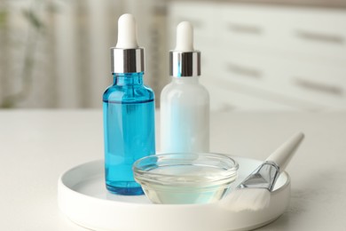 Photo of Peeling procedure. Bottles of chemical peel, bowl with liquid and brush on white table indoors