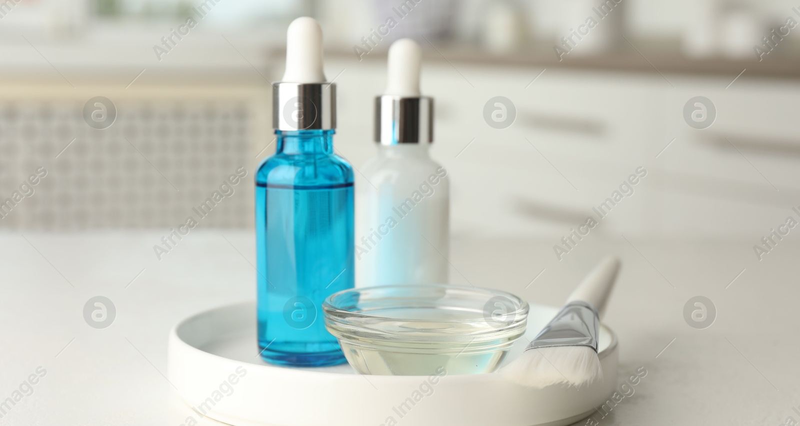 Photo of Peeling procedure. Bottles of chemical peel, bowl with liquid and brush on white table indoors