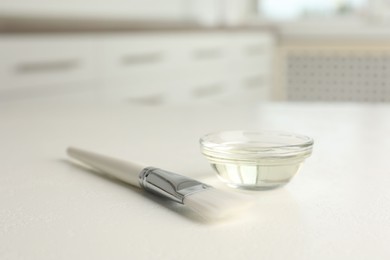 Peeling procedure. Chemical peel liquid in bowl and brush on white table indoors. Space for text