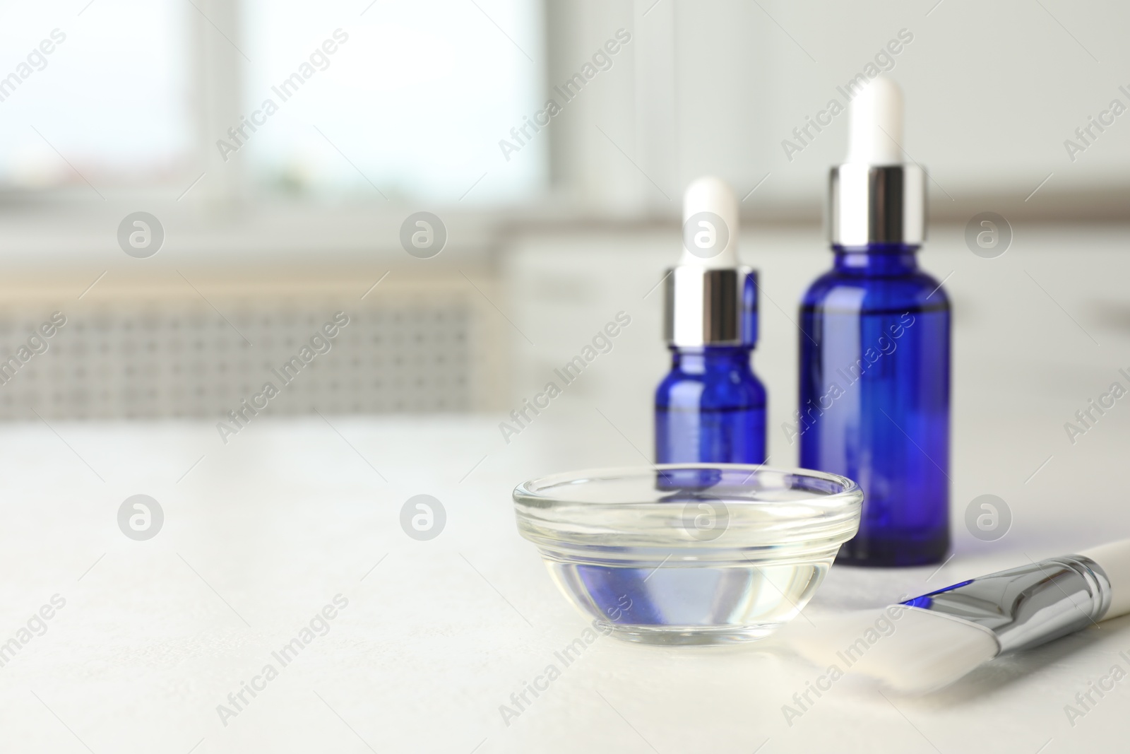 Photo of Peeling procedure. Bottles of chemical peel, bowl with liquid and brush on white table. Space for text