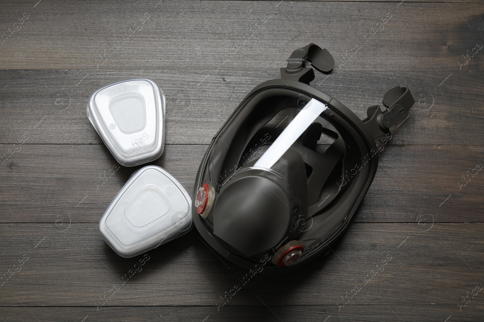 Photo of Respirator mask and filters on wooden table, top view