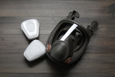 Respirator mask and filters on wooden table, top view