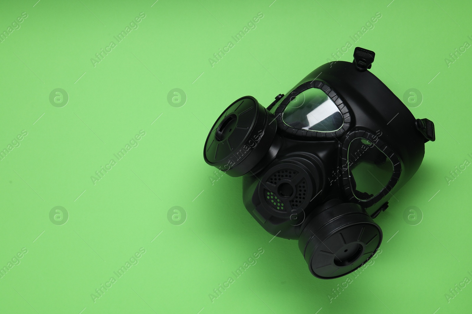 Photo of One gas mask on green background, top view and space for text. Safety equipment