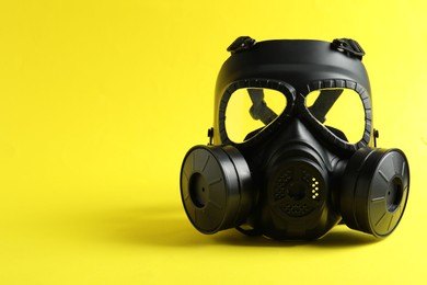 Photo of One gas mask on yellow background, space for text. Safety equipment