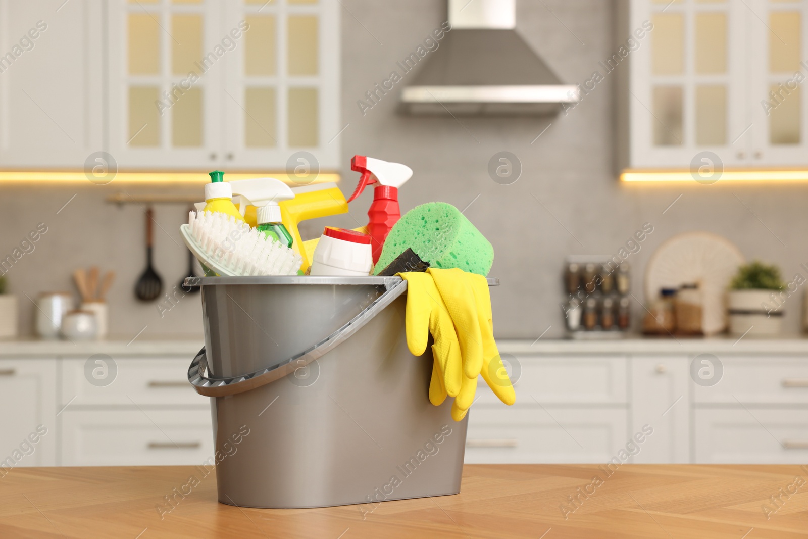 Photo of Cleaning service. Bucket with supplies on table in kitchen. Space for text