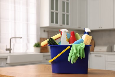 Photo of Cleaning service. Bucket with supplies on table in kitchen. Space for text