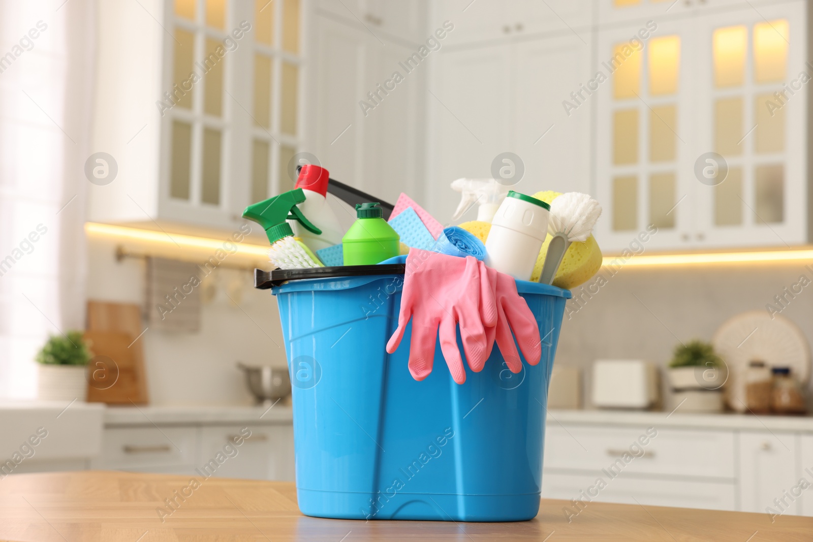 Photo of Cleaning service. Bucket with supplies on table in kitchen