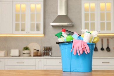 Photo of Cleaning service. Bucket with supplies on table in kitchen. Space for text