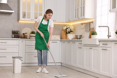 Cleaning service worker washing floor with mop in kitchen