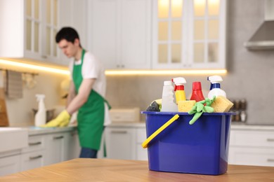 Professional janitor working in kitchen, focus on bucket with supplies. Cleaning service