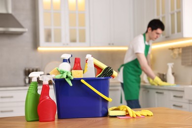 Photo of Professional janitor working in kitchen, focus on bucket with supplies. Cleaning service