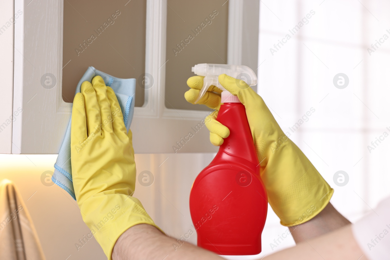 Photo of Professional janitor cleaning cabinet in kitchen, closeup