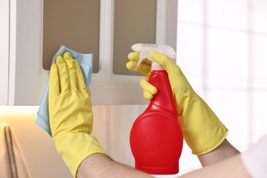 Photo of Professional janitor cleaning cabinet in kitchen, closeup