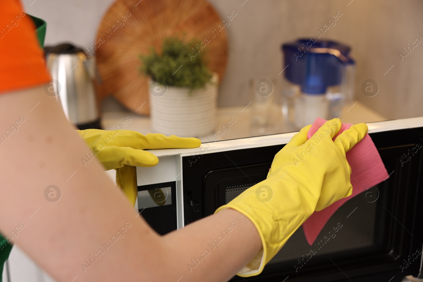 Photo of Professional janitor cleaning microwave oven in kitchen, closeup