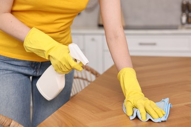 Professional janitor wearing uniform cleaning table in kitchen, closeup