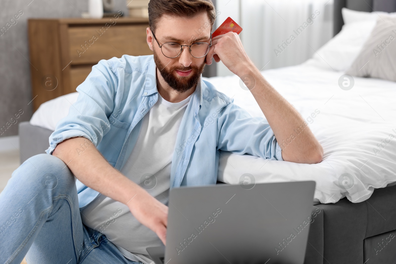 Photo of Online banking. Young man with credit card and laptop paying purchase at home