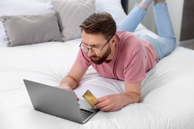 Photo of Online banking. Young man with credit card and laptop paying purchase at home