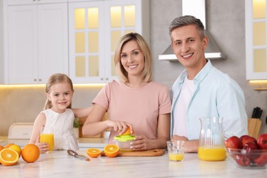 Happy family with juicer and fresh products making juice at white marble table in kitchen