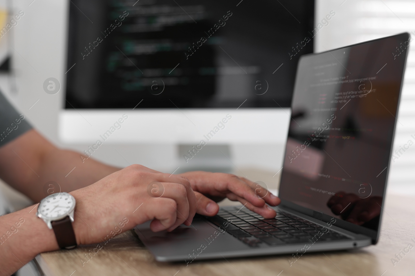 Photo of Programmer working with laptop at desk in office, closeup