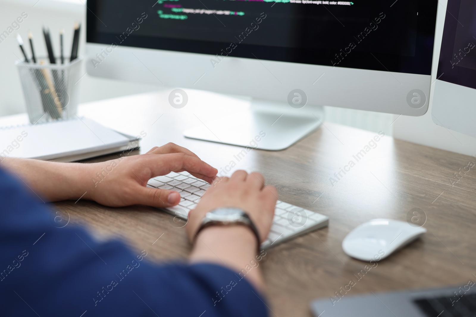 Photo of Programmer working with computer at desk in office, closeup