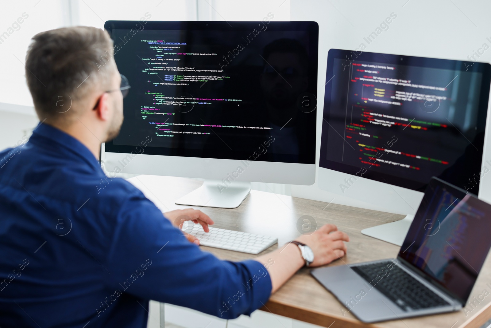 Photo of Young programmer working at desk in office, back view