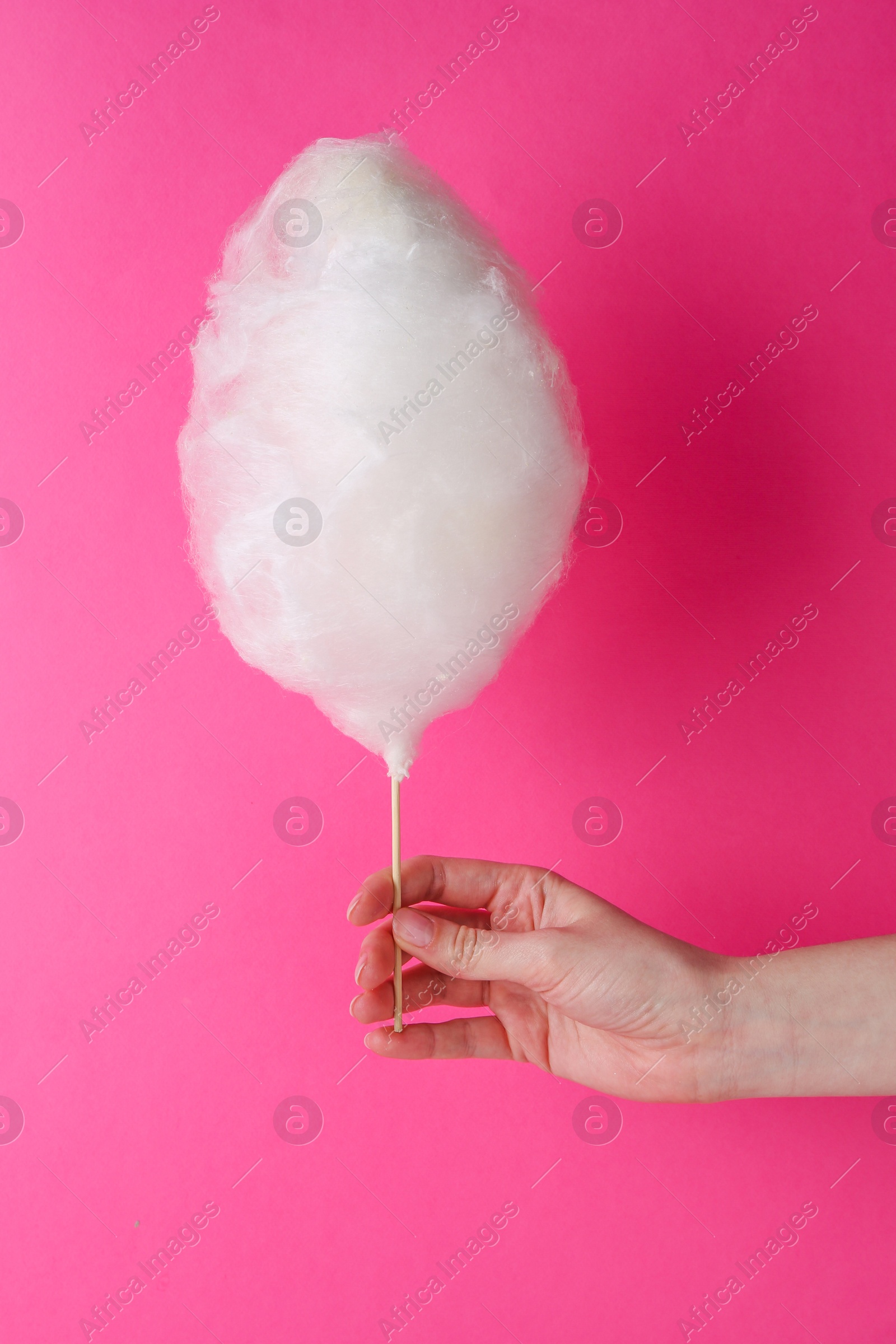Photo of Woman holding sweet cotton candy on pink background, closeup