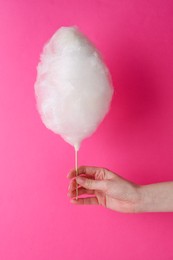Woman holding sweet cotton candy on pink background, closeup