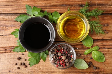 Balsamic vinegar in bowl, oil, herbs and spices on wooden table, flat lay