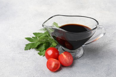 Photo of Balsamic vinegar in gravy boat, tomatoes, parsley and dill on gray textured table