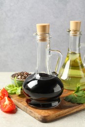 Balsamic vinegar in glass jug, oil, tomatoes, herbs and spices on gray textured table