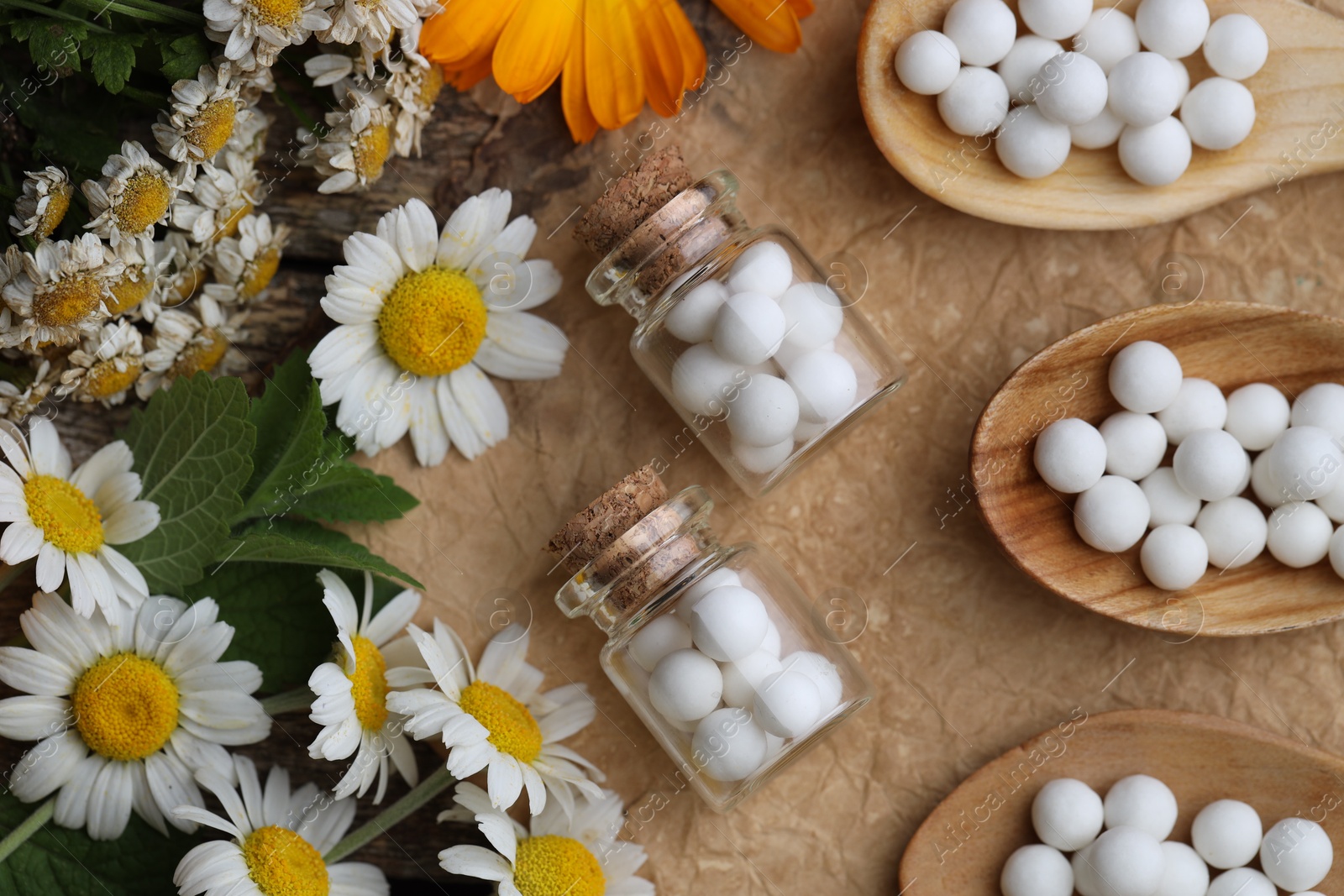 Photo of Homeopathic remedy. Flat lay composition with many pills, bottles and flowers on wooden table