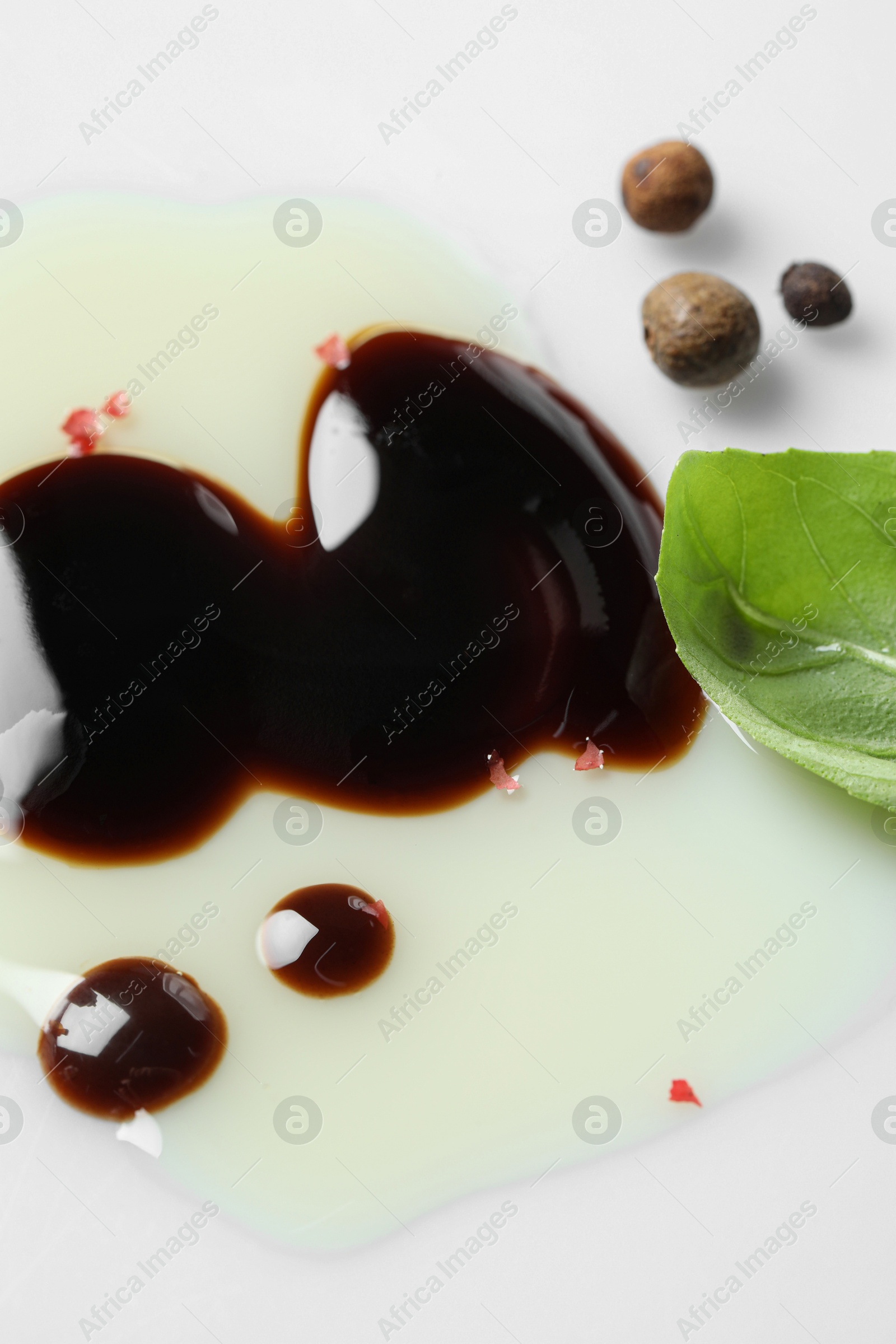 Photo of Delicious balsamic vinegar with olive oil, basil and peppercorns on white background, closeup