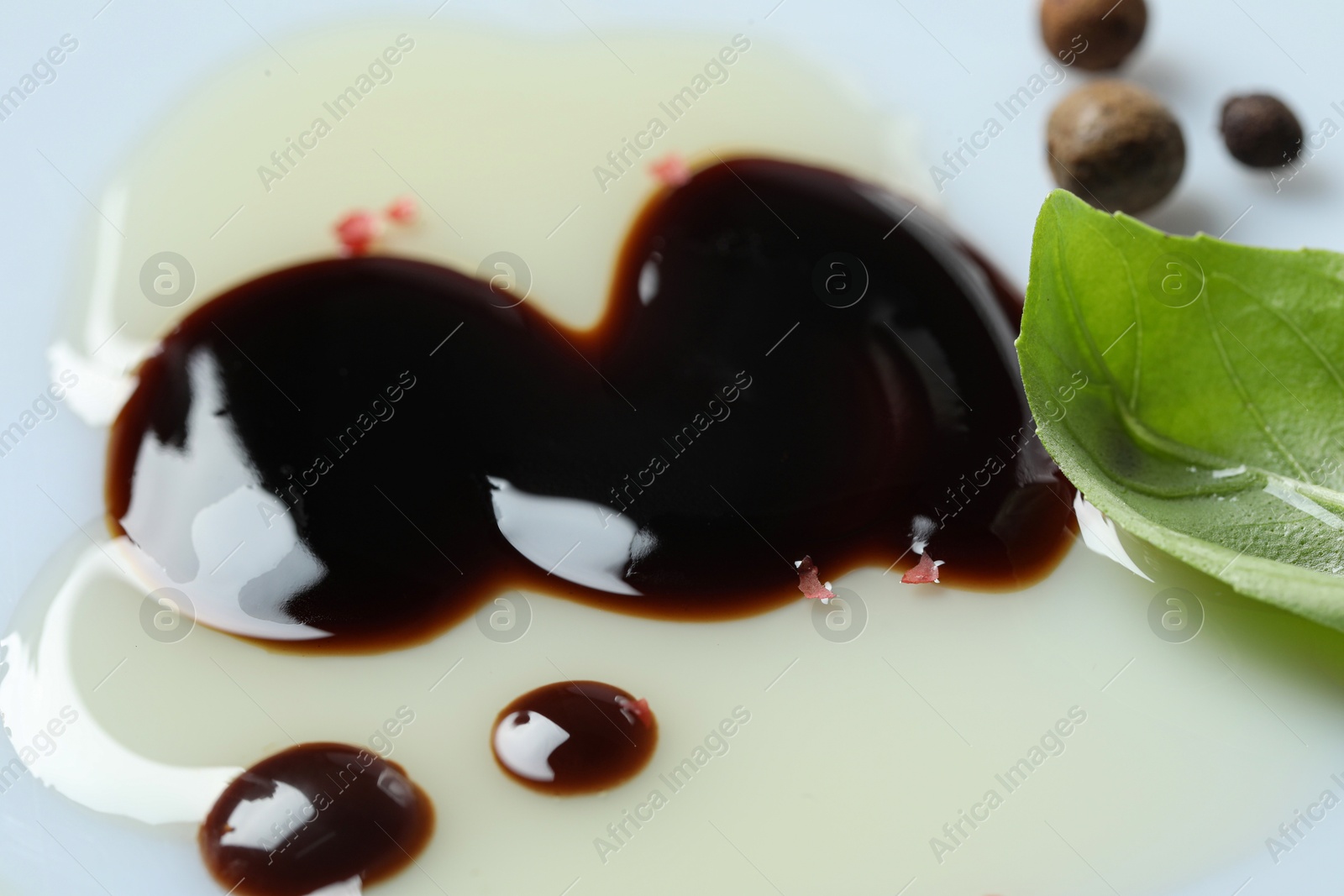 Photo of Delicious balsamic vinegar with olive oil, basil and peppercorns on white background, closeup