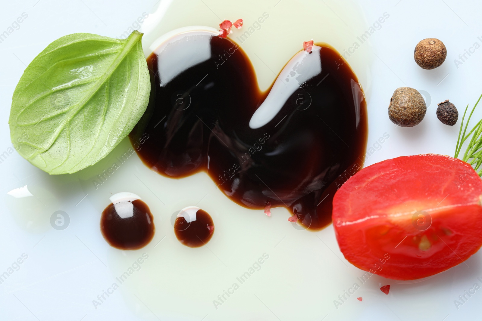 Photo of Delicious balsamic vinegar with olive oil, basil, tomato and peppercorns on white background, closeup